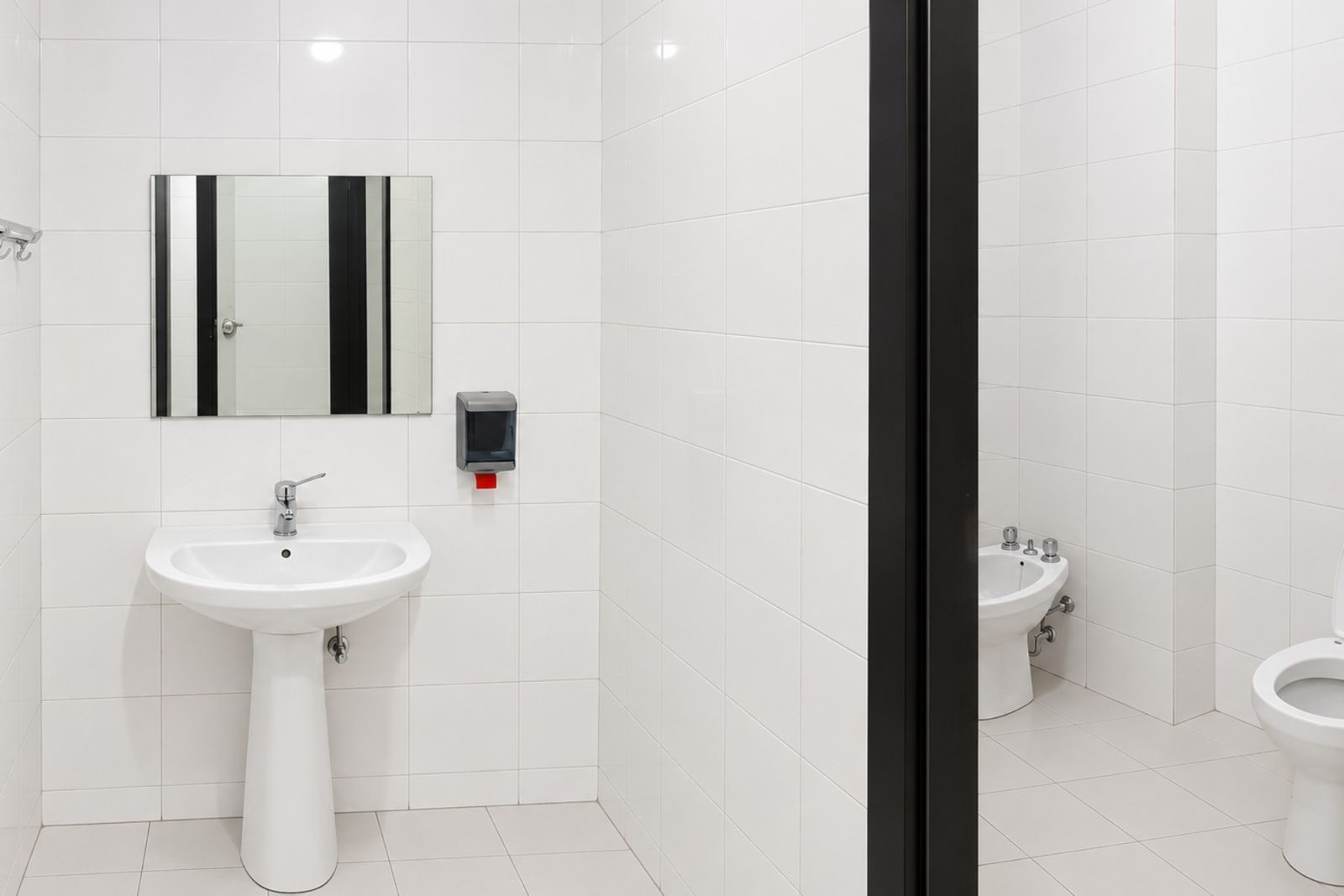 Antibagno con lavandino e bagni rivestiti in piastrelle bianche
